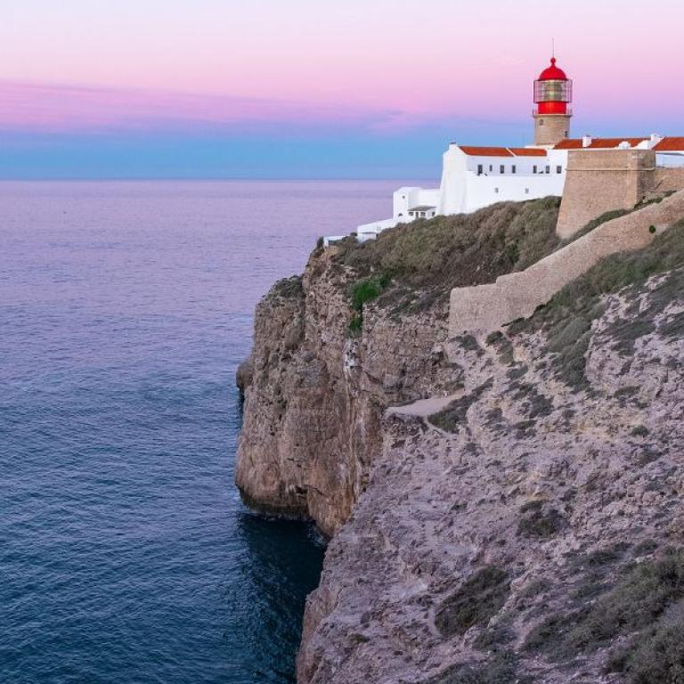 lighthouse on the cliff in sagres at sunset