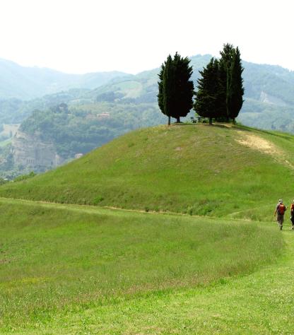 green hill with walkers on Via degli Dei route