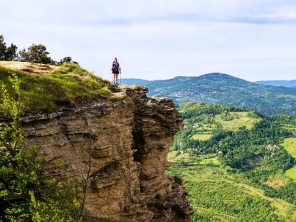 green hill with walkers on Via degli Dei route