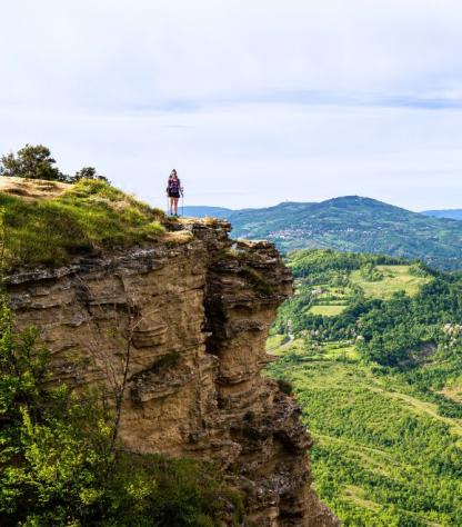 green hill with walkers on Via degli Dei route
