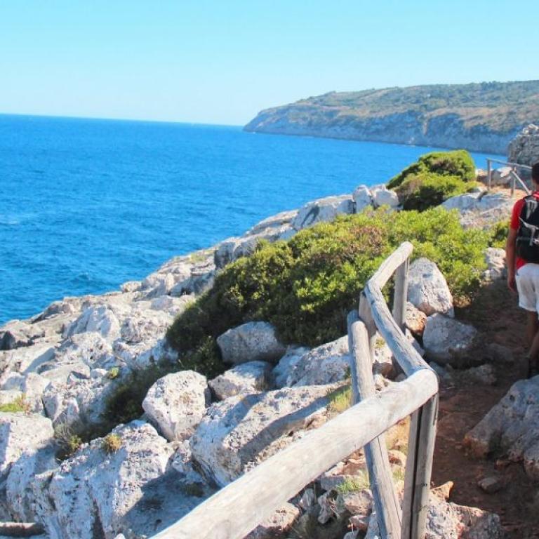 hiker on Via Costa Salentina path by rocky sea
