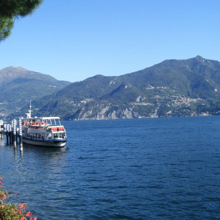 Traghetto attraccato a un molo sul Lago di Como con montagne in lontananza