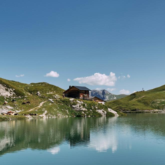 Refugio junto a un lago alpino tranquilo, un clásico de las vacaciones en Austria a pie.