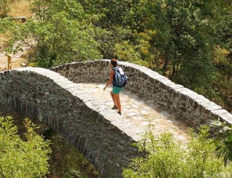 hiker on an ancient stone bridge during a tuscany walking holiday