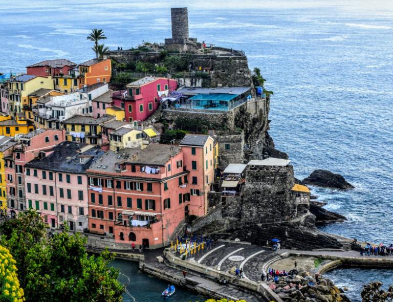 Vernazza’s harbor and pastel houses rising above the sea on a panoramic trail in the Cinque Terre