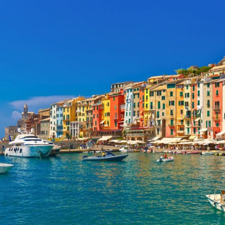 Portovenere's port with moored boats and colorful houses.