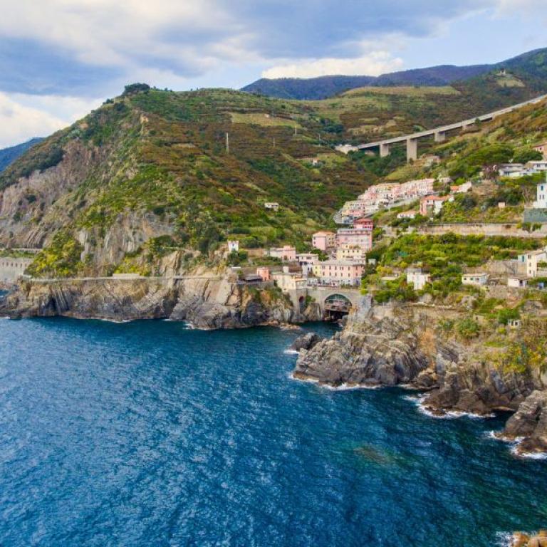 Aerial view of Riomaggiore perched on dramatic cliffs above the blue Ligurian Sea along scenic walking routes