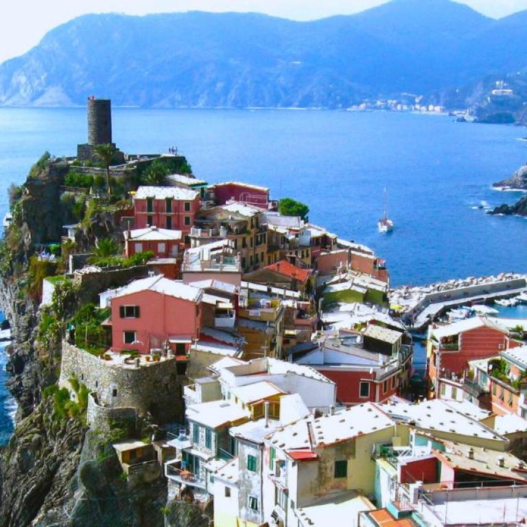 Vernazza village and watchtower rising above the deep-blue sea on a classic trail of the Cinque Terre
