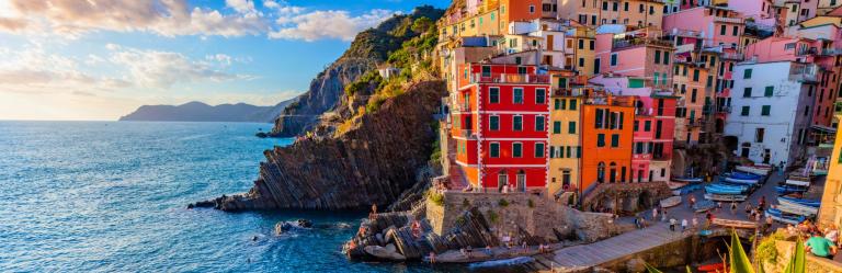 Colorful Riomaggiore houses on the cliff at sunset overlooking the Ligurian Sea on a scenic Cinque Terre hiking tour