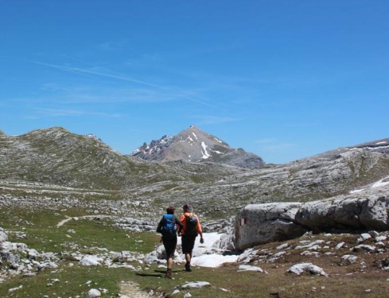 Pareja de excursionistas cruzando un altiplano alpino durante una aventura de senderismo en Italia