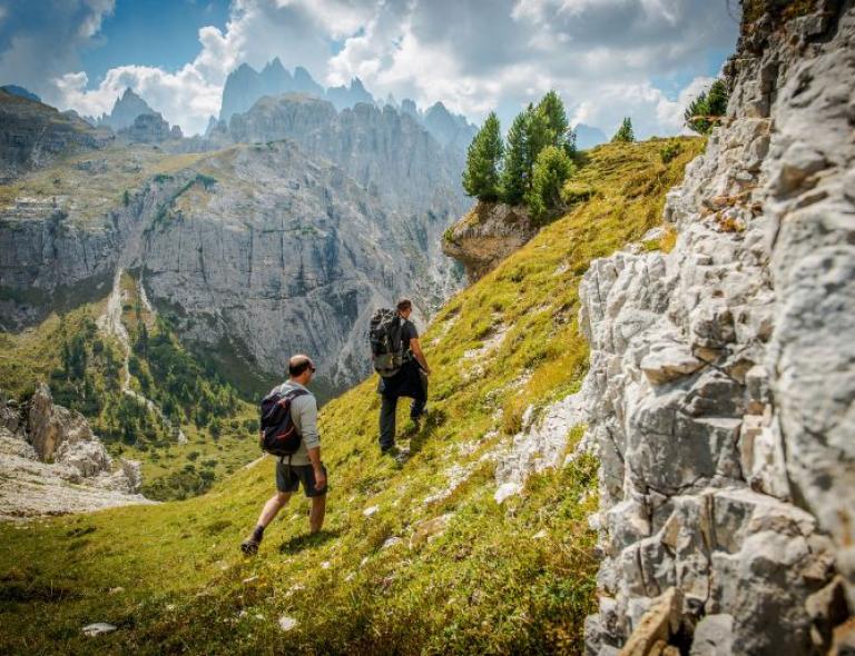 Senderistas subiendo las laderas rocosas de las Dolomitas, rodeados de vistas impresionantes – una imagen clásica del senderismo en Italia
