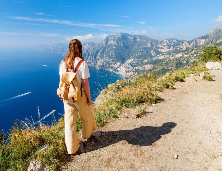 Hiker enjoying sweeping sea views from a cliffside trail on a scenic Amalfi Coast walking holiday.