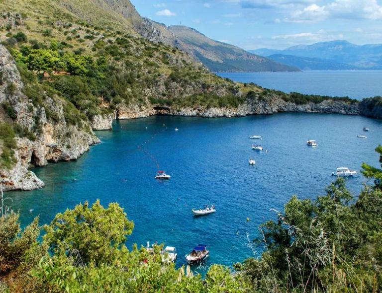 Hidden turquoise bay dotted with boats along a peaceful route during Amalfi Coast walking holidays.