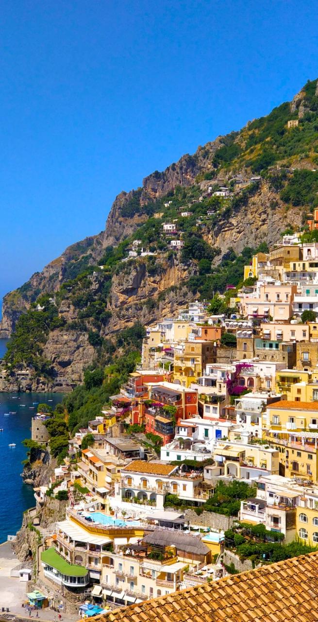 Colorful Amalfi houses rising over the bay with boats floating on calm waters during Amalfi Coast hiking tours.