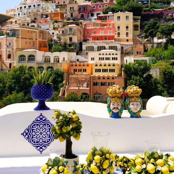 Colorful Positano houses overlooking a terrace decorated with lemons and ceramics during Amalfi Coast hiking tours.