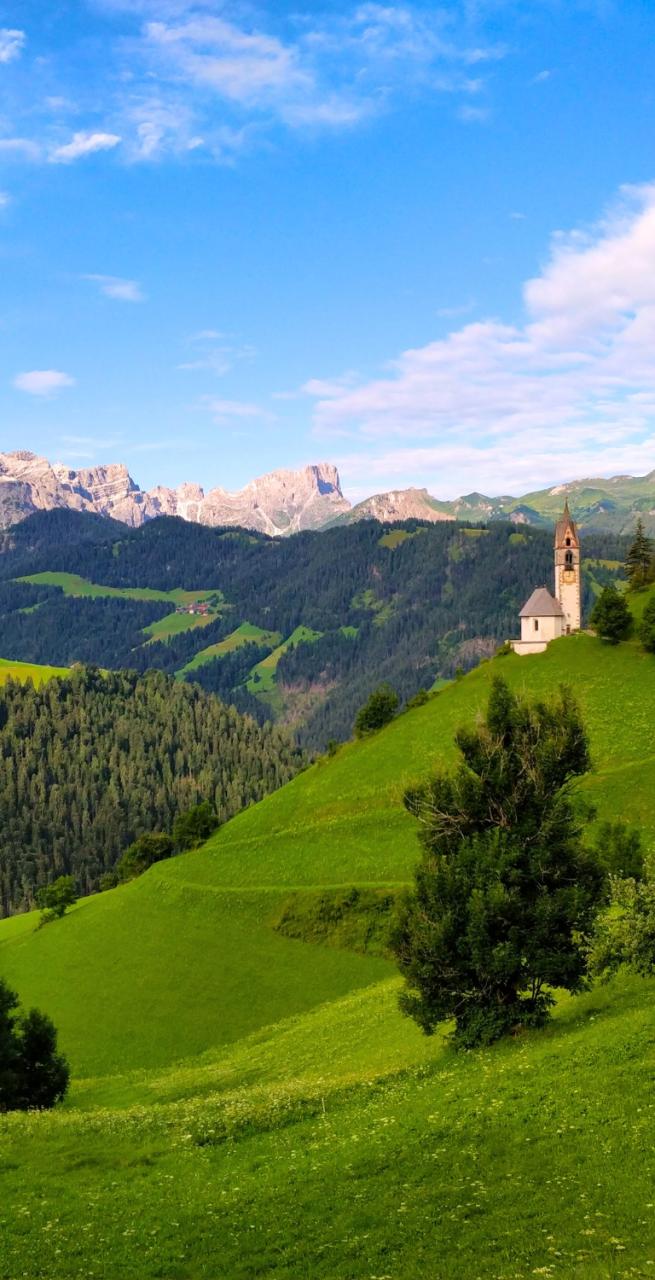Senderistas caminando entre prados alpinos en unas Vacaciones en el Norte de Italia