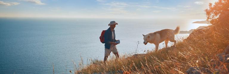 A man hiking on a hill with his dog