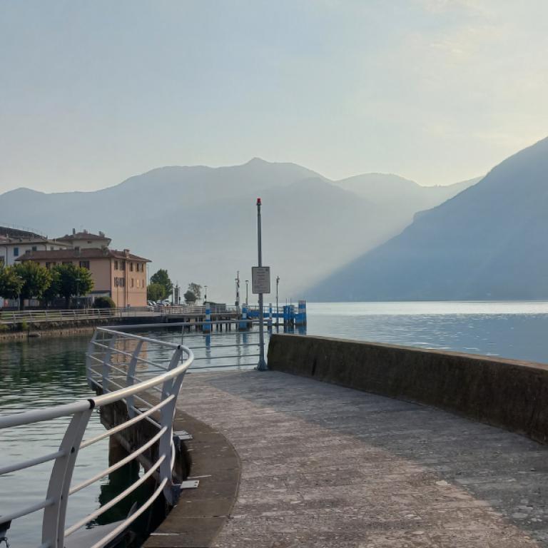 molo sul lago di iseo con vista sulle montagne e un paese di pescatori
