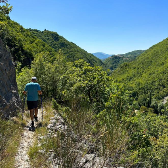 Pilgrim walking through lush valleys and spring landscapes on St. Benedict’s Way