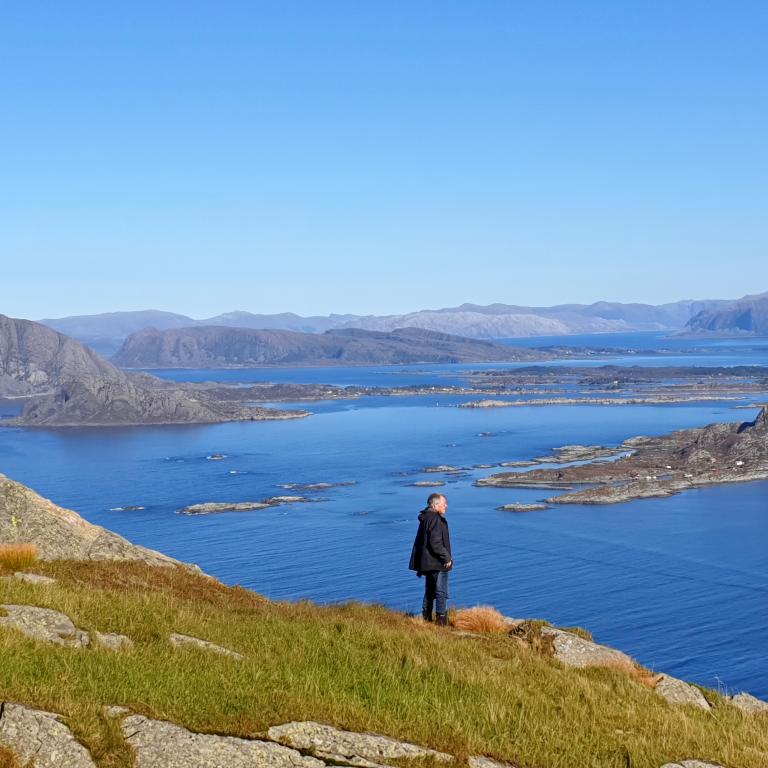 Viandante che ammira il panorama di isole e fiordi dalla costa lungo il Cammino Costiero di Sant’Olav