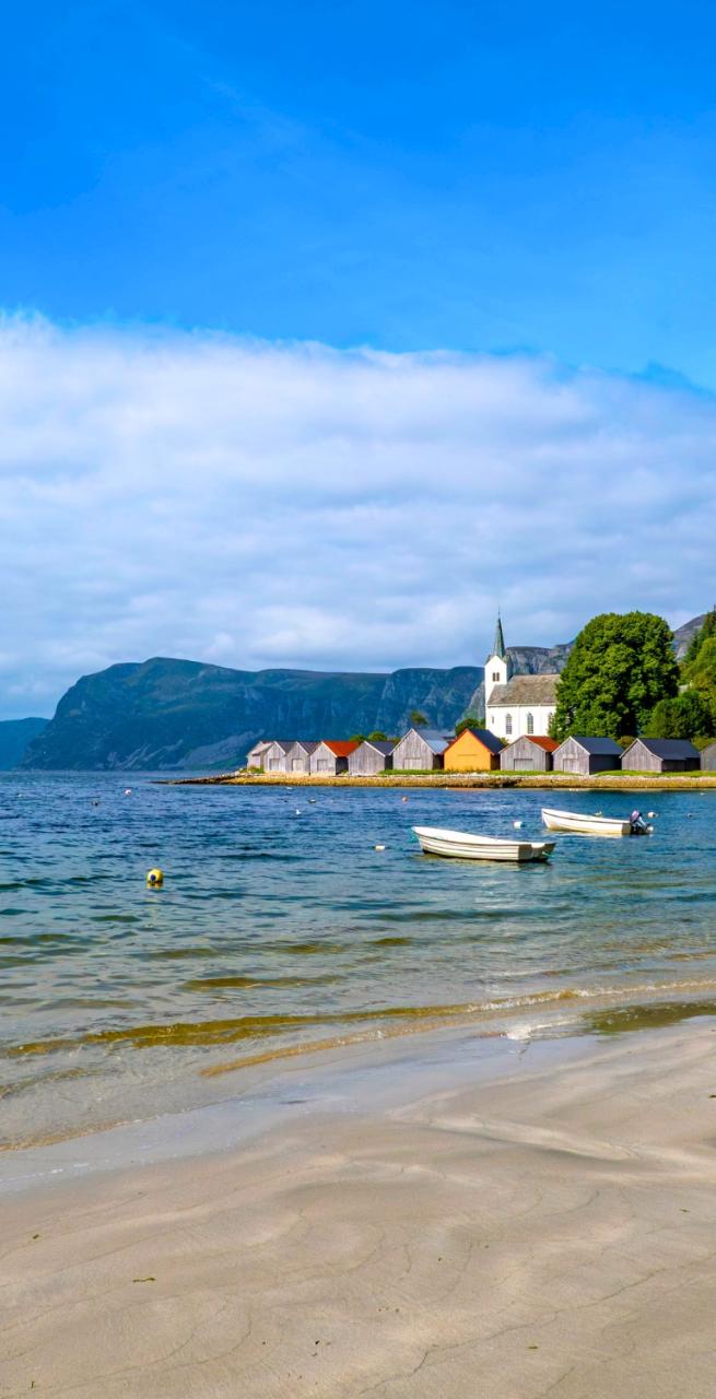 Viandante che ammira il panorama di isole e fiordi dalla costa lungo il Cammino Costiero di Sant’Olav