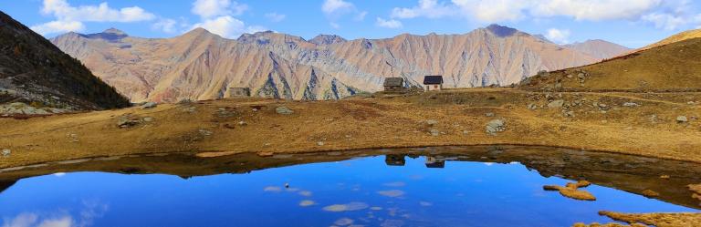 Alpine lake reflecting rugged mountain peaks along the Piedmont alpine walking tour