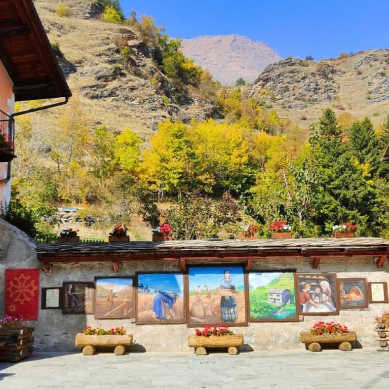 Colorful village square with murals and flowers along the Piedmont alpine walking tour